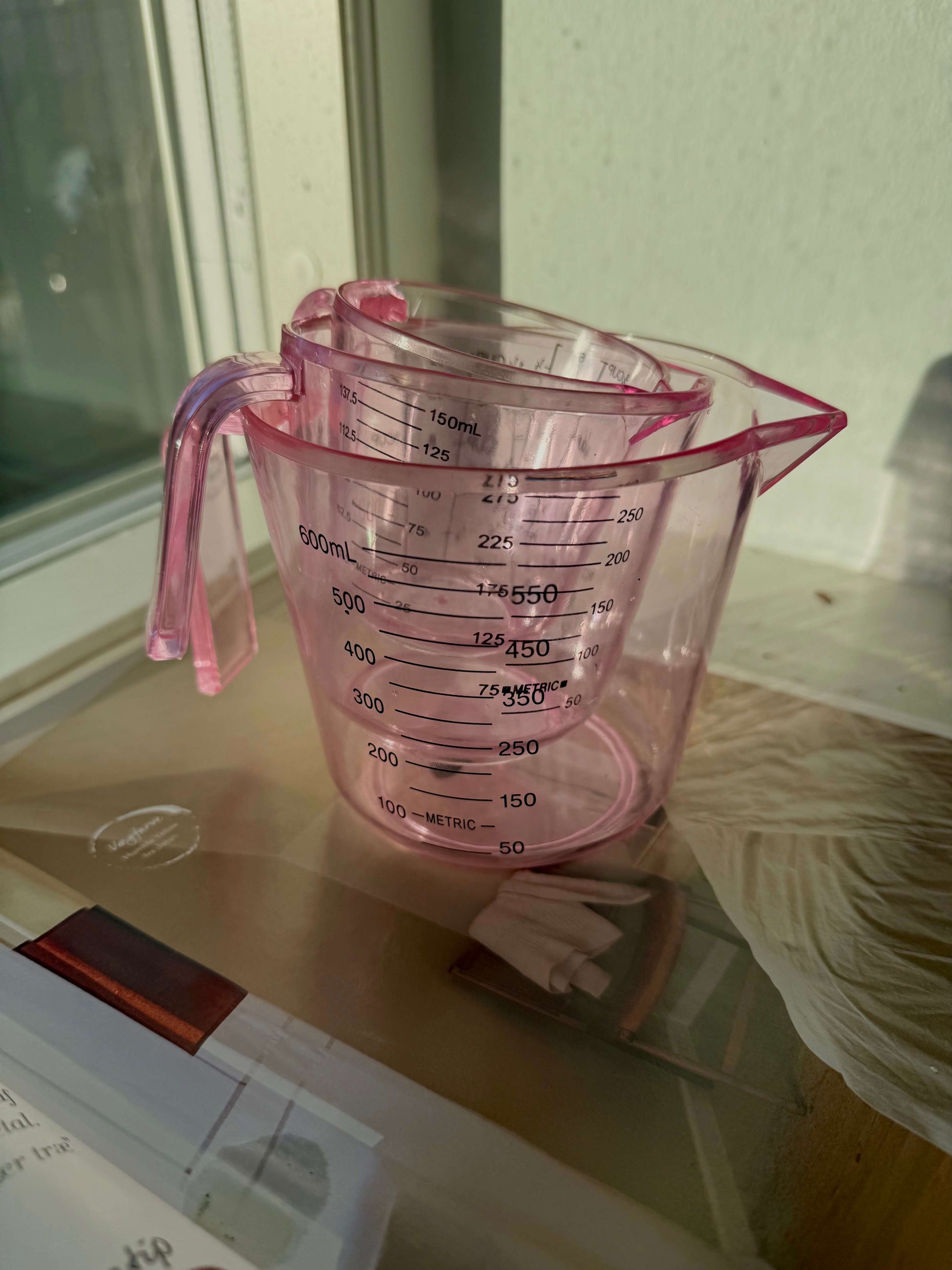 Lyserøde målebægre stablet sammen på køkkenbordet – praktisk og dekorativt