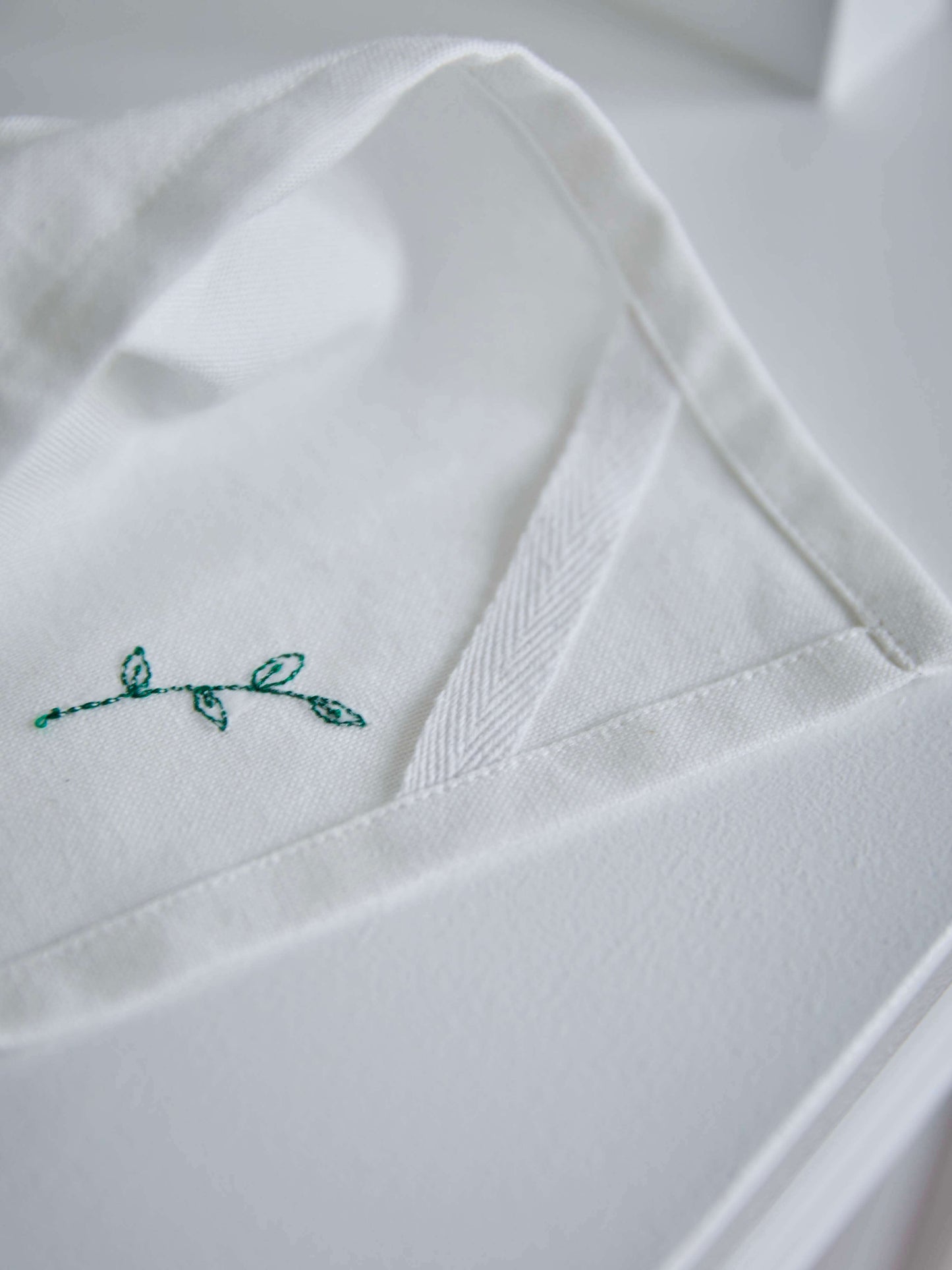 Flower viskestykke med håndbroderede blomster, hængende på en knage – smukt og funktionelt køkkentekstil i økologisk bomuld.