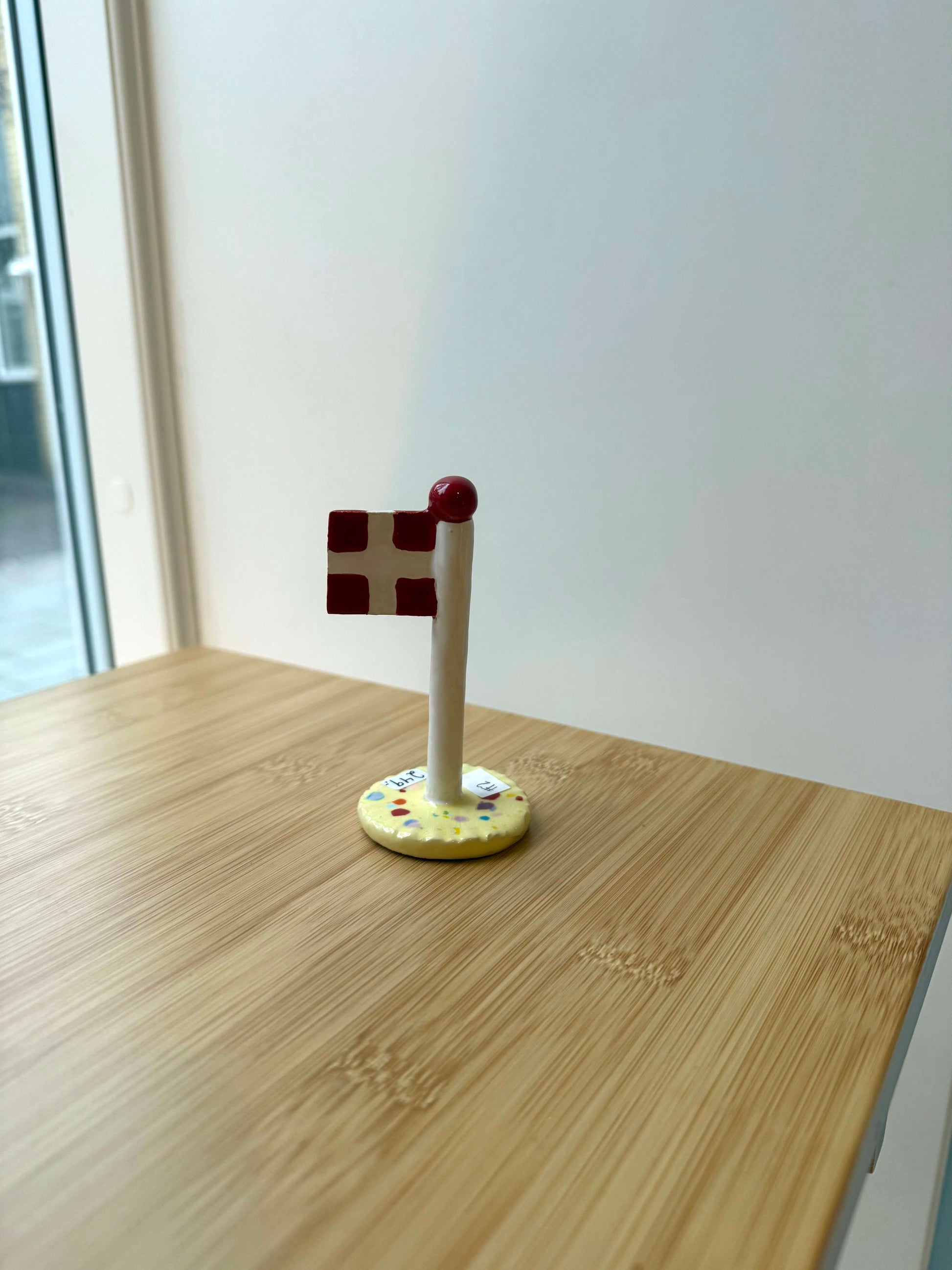 Keramikflag på træbord med gul glasur og dannebrog