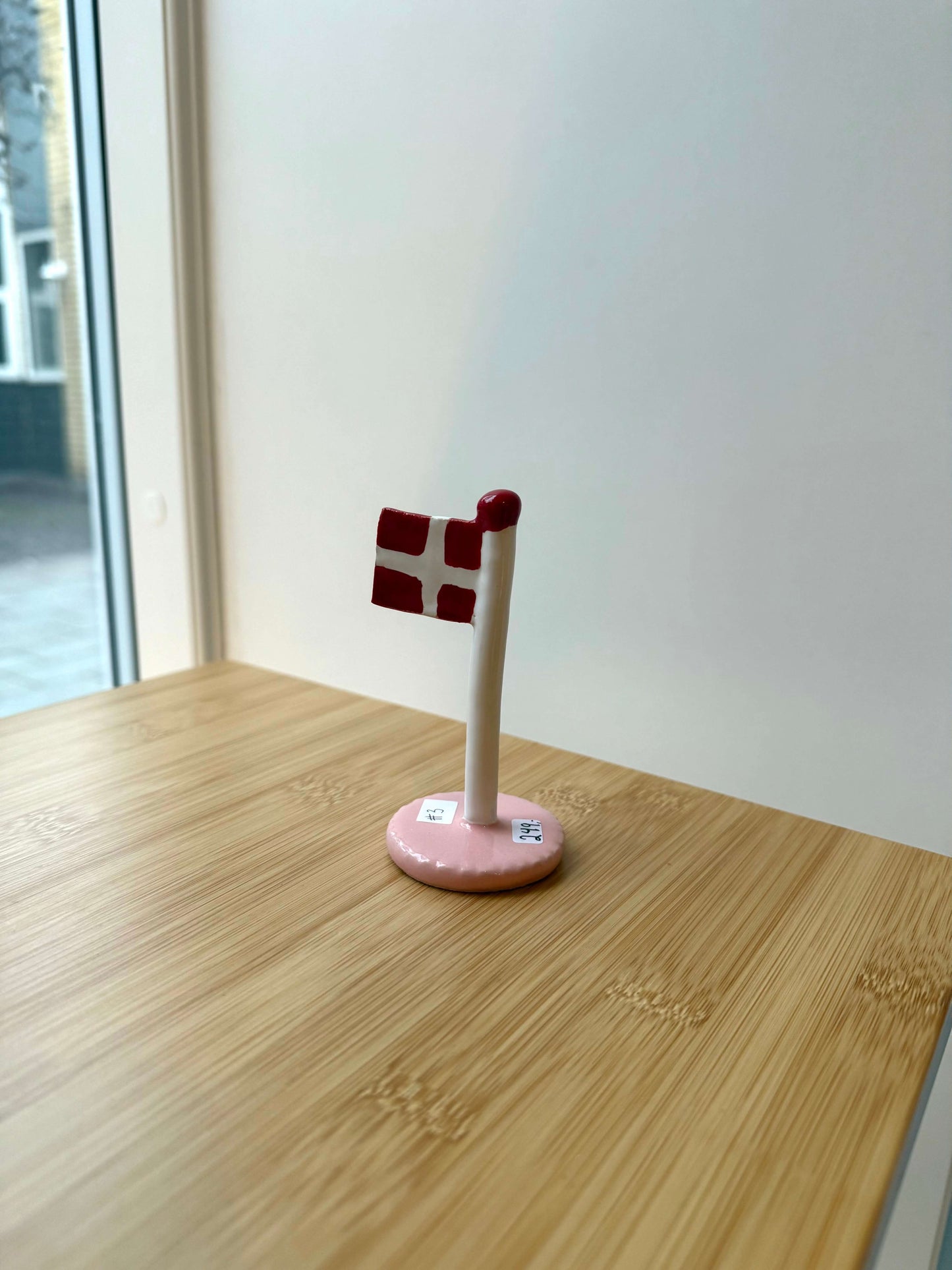 Keramikflag på træbord med lyserød glasur og dannebrog