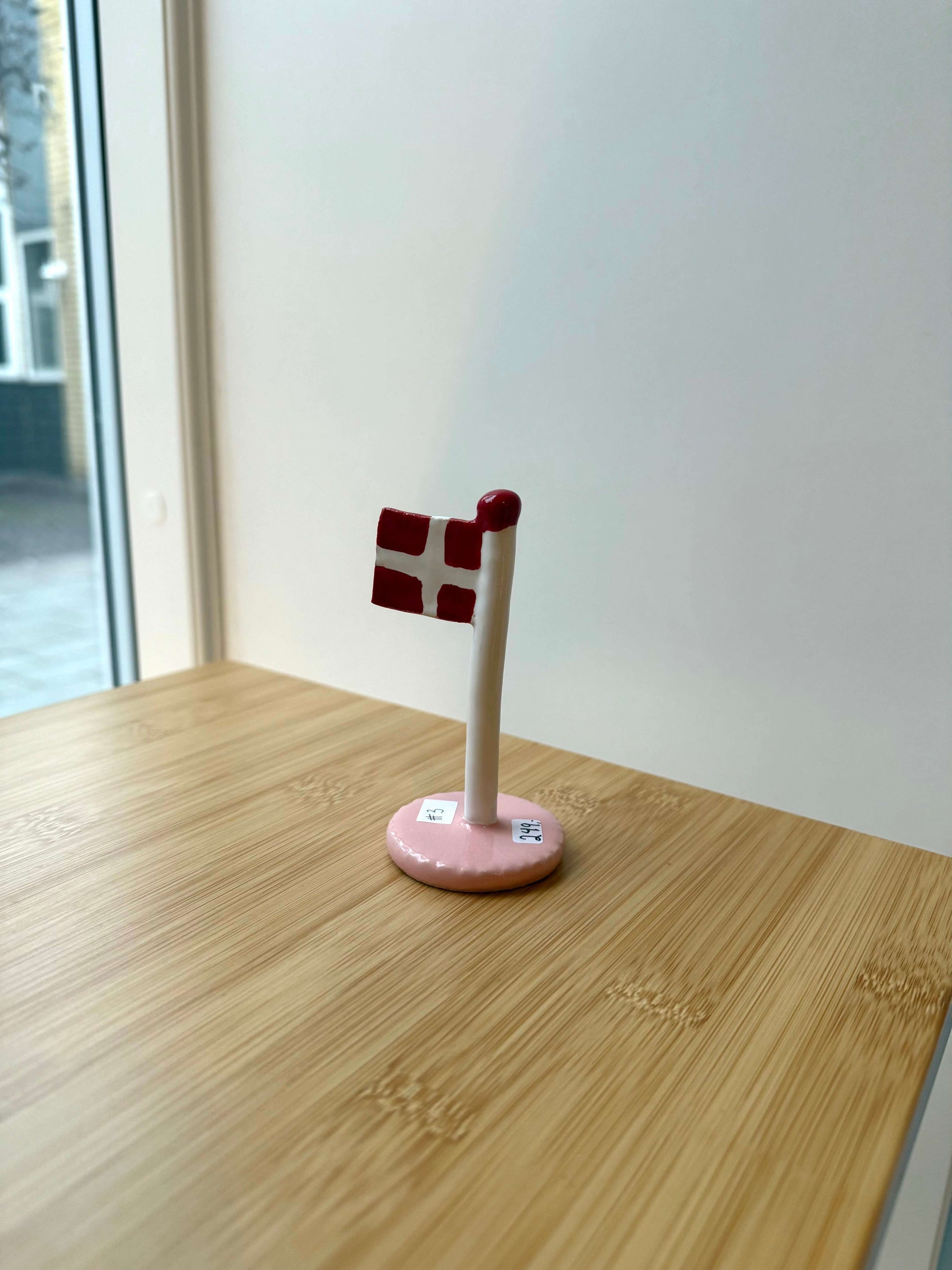 Keramikflag på træbord med lyserød glasur og dannebrog