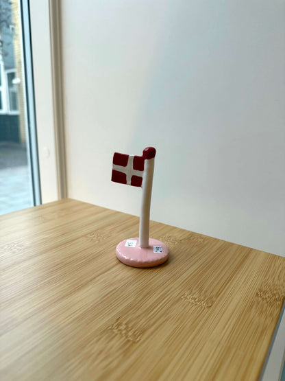 Keramikflag på træbord med lyserød glasur og dannebrog