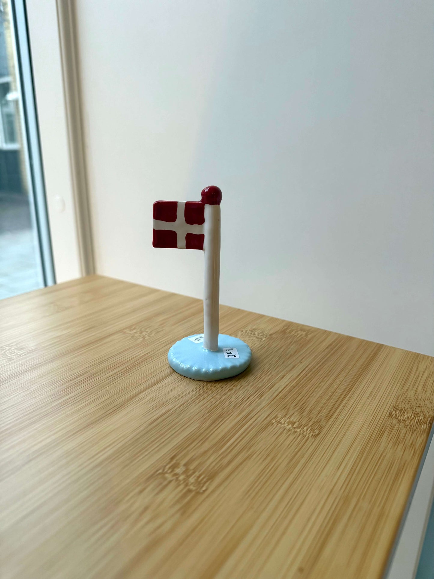 Keramikflag på træbord med lyseblå glasur og dannebrog
