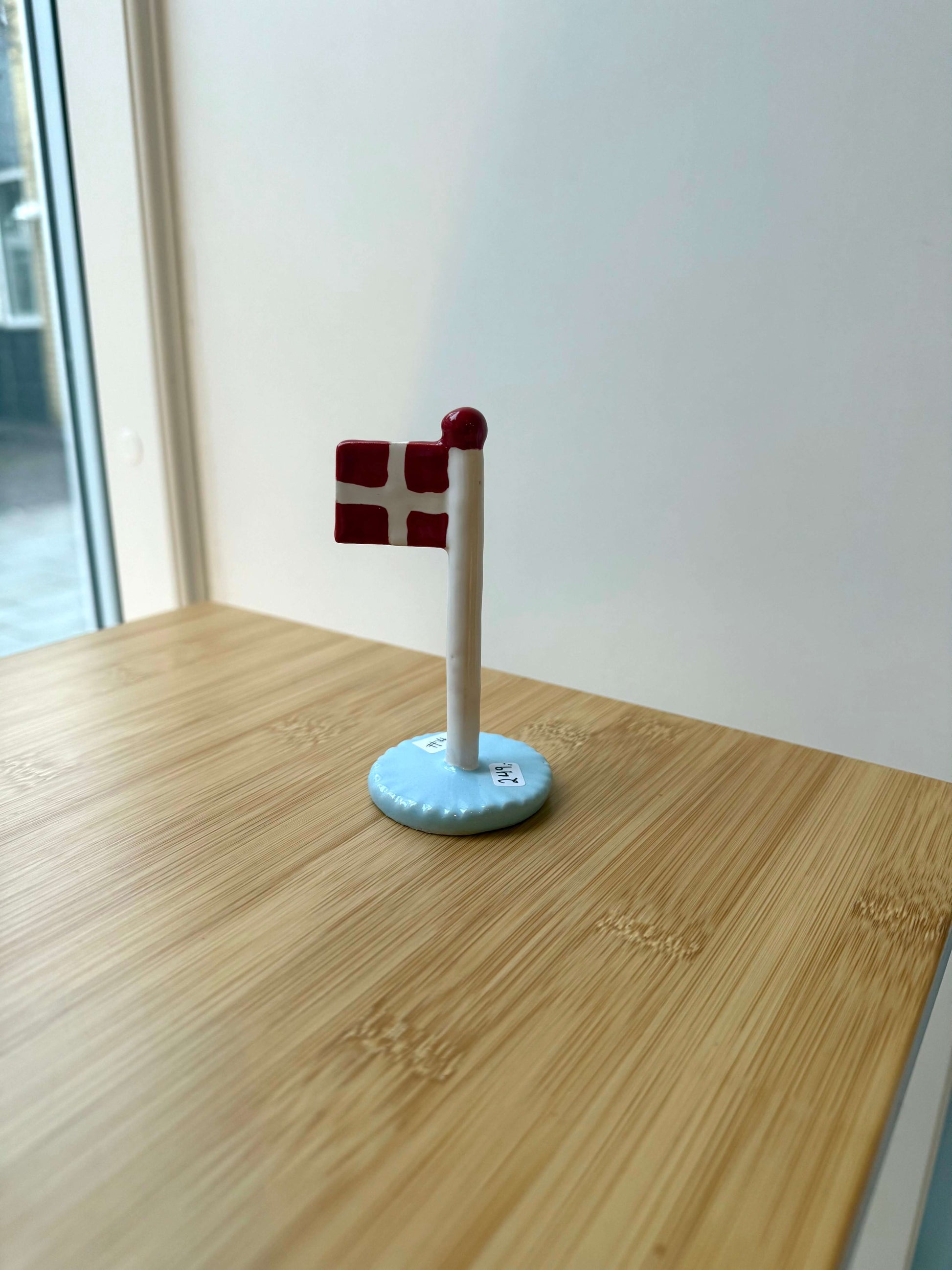 Keramikflag på træbord med lyseblå glasur og dannebrog