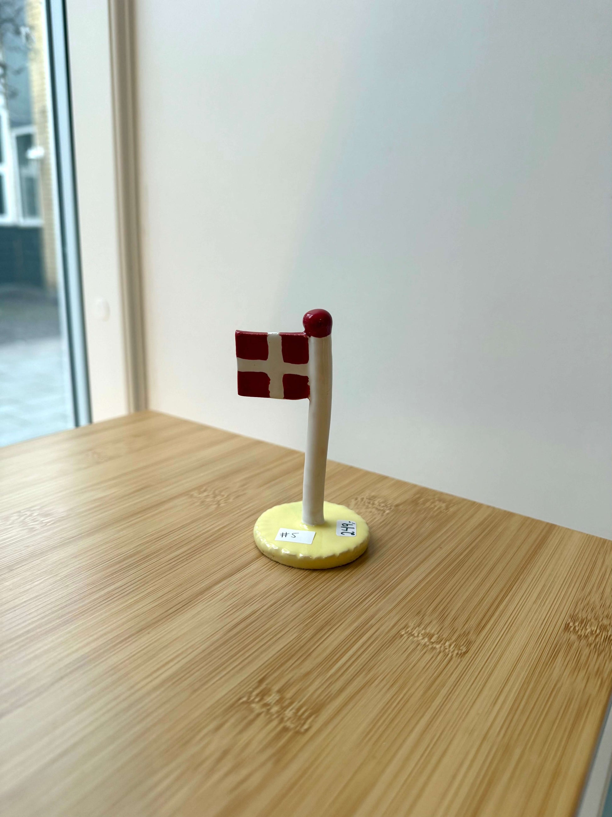 Keramikflag på træbord med gul glasur og dannebrog