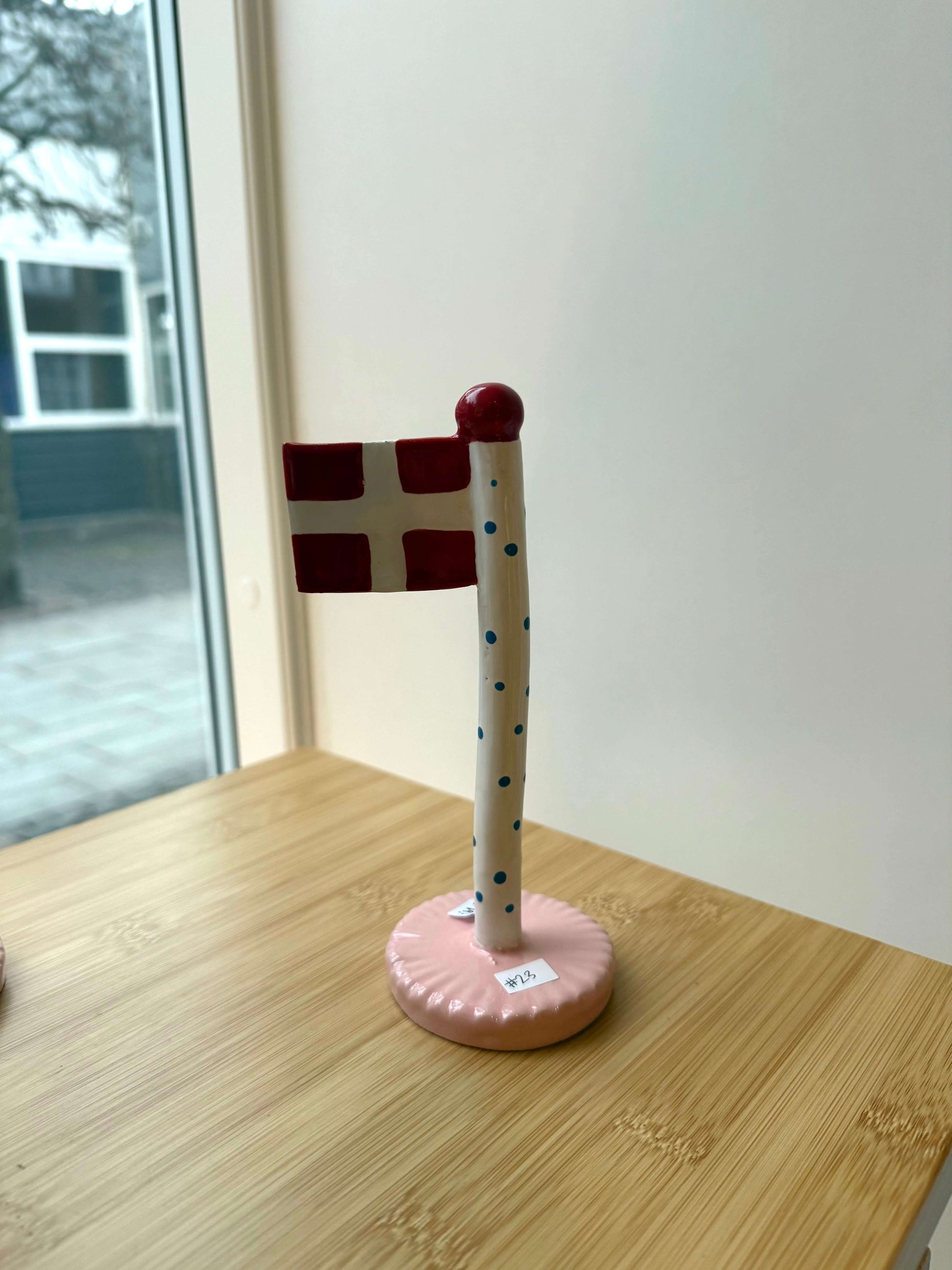 keramikflag med blå polka på stang og lyserød bund