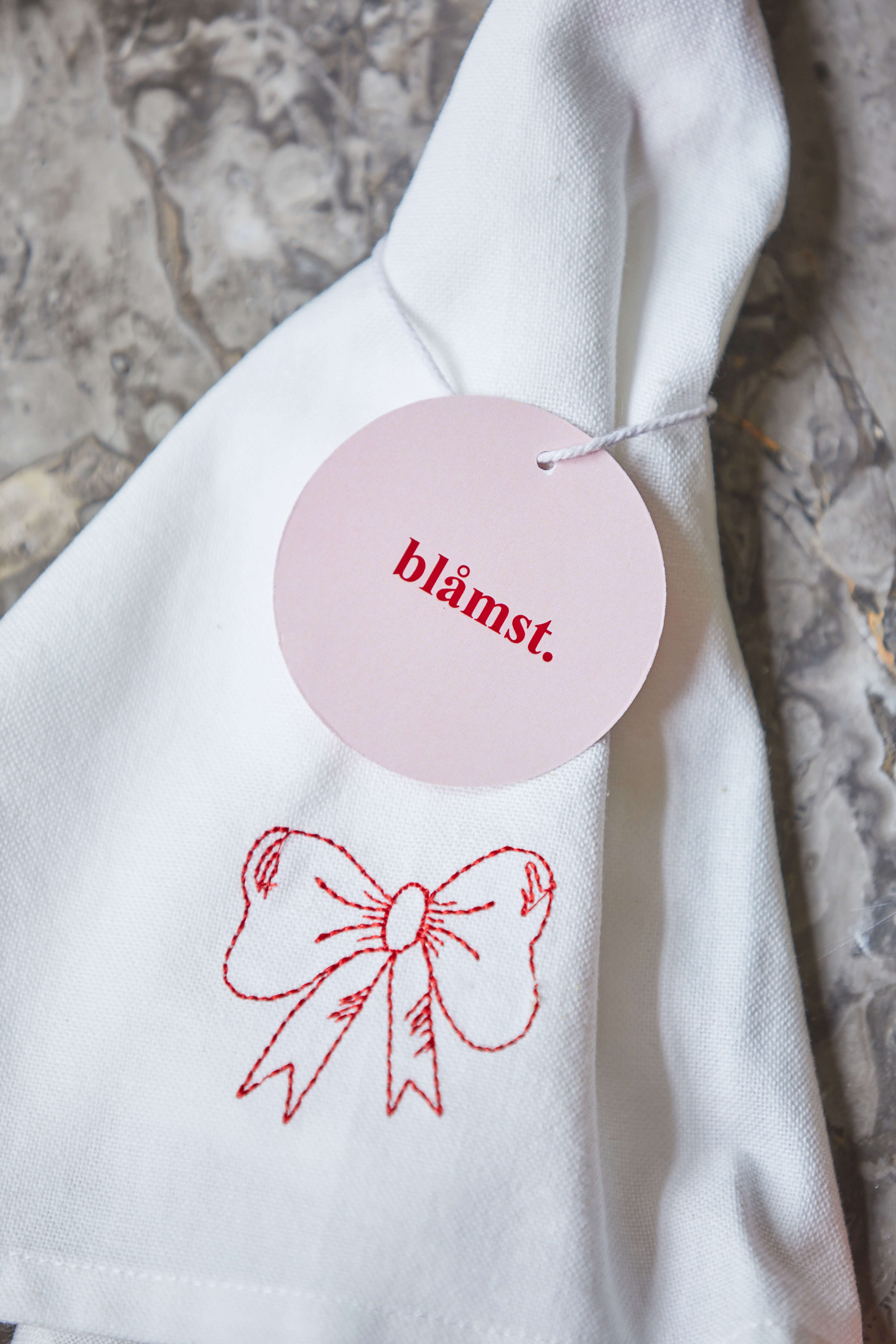 Bow viskestykke med rødt broderi og label, foldet og klar til brug.