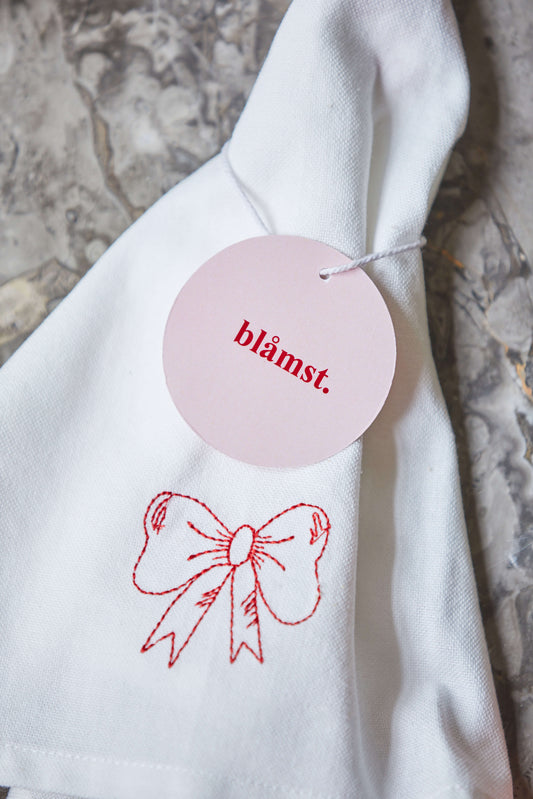Bow viskestykke med rødt broderi og label, foldet og klar til brug.