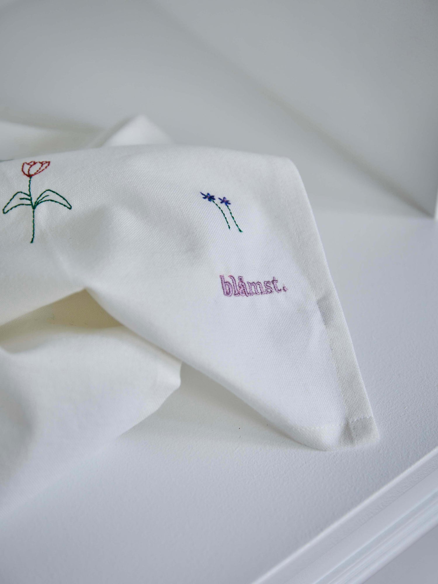 Nærbillede af Flower viskestykke fra Blåmst – broderede blå og røde blomster på blødt, absorberende bomuld."