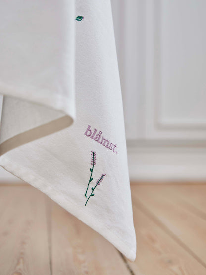 Blåmst Flower Dug i brug – en stemningsfuld borddækning med broderede blomster, der tilføjer varme og karakter til måltidet.