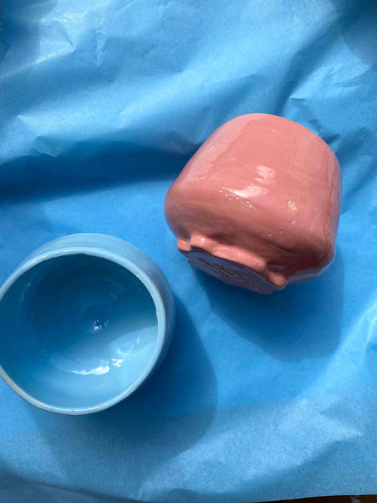 To håndlavede cortado kopper i blå og rød keramik fra Kaasgaard Ceramics, placeret på blåt stof.